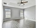 Spacious main bedroom with tray ceilings, wood-look floors, and dual windows for natural light at 9551 Maxson Dr, Land O Lakes, FL 34638