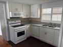Well-lit kitchen featuring white cabinetry, tile backsplash, and stainless steel sink at 10208 Oak Hill Dr, Port Richey, FL 34668