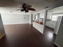 Open-concept living space with dark hardwood floors, ceiling fan, and view of kitchen at 10208 Oak Hill Dr, Port Richey, FL 34668