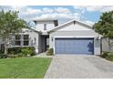 Charming single-Gathering home with a blue garage door, manicured lawn, and lush landscaping at 10736 Whitland Grove Dr, Riverview, FL 33578