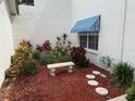Beautiful landscaped yard with bench, flowering plants, bark, and awning over window at 11351 Shipwatch Ln # 1844, Largo, FL 33774