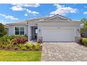 Attractive home featuring a two-car garage, paver driveway, and a landscaped front yard at 11470 Myakka Blue Dr, Venice, FL 34293