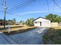 Inviting single-story home boasts a long driveway, attached garage, and is surrounded by a lush landscape at 13018 Clay Ave, Largo, FL 33773
