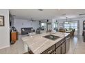 Kitchen featuring a large island with sink, seating and a view into the living and dining areas at 16704 Sunburst Lake St, Wimauma, FL 33598