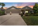 Charming single-story home with a three-car garage and well-manicured landscaping at dusk at 17731 Bright Wheat Dr, Lithia, FL 33547