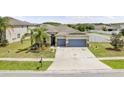 Inviting single-story home boasting a two-car garage, manicured lawn, and lush palm tree landscaping at 18677 Milton Keynes Ct, Land O Lakes, FL 34638