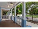 Inviting front porch with white columns, hanging plants, and a wood-planked floor at 2130 W Spruce St, Tampa, FL 33607