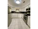 Bright, updated kitchen featuring stainless steel appliances, white cabinets, and sleek black backsplash and tiled floor at 2400 13Th S Ave, St Petersburg, FL 33712