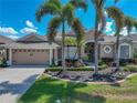 Attractive single-Gathering home featuring mature palm trees, colorful landscaping, and a well-maintained lawn and driveway at 2908 89Th E Ave, Parrish, FL 34219