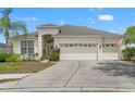Inviting one-story home featuring a three-car garage, lush landscaping, and a well-manicured lawn at 4214 Canongate Ct, Spring Hill, FL 34609