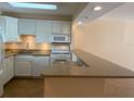 Well-lit kitchen featuring white cabinets, granite countertops, and modern appliances at 845 S Gulfview Blvd # 107, Clearwater Beach, FL 33767