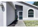 Close-up of the front entrance featuring a screen door, arched window, and manicured landscaping at 13613 Laraway Dr, Riverview, FL 33579