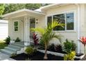 A close-up view showing a quaint front porch adorned with lush landscaping, providing a serene entrance to the home at 1443 Paloma Ln, Dunedin, FL 34698