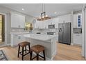 Bright kitchen with white cabinets, quartz countertops, stainless steel appliances, and island with bar stools at 19101 Marisa Ridge Pl, Tampa, FL 33647