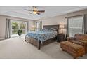 Spacious main bedroom featuring a tray ceiling, ensuite bathroom, and a private balcony overlooking the yard at 19101 Marisa Ridge Pl, Tampa, FL 33647