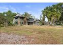 View of the house's side and front, with mature palm trees and a gravel and grass yard at 2493 6Th Sw Ave, Largo, FL 33770
