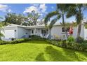 Inviting single-story home with a green lawn, palm trees, and a cheerful, landscaped front yard at 5235 42Nd S St, St Petersburg, FL 33711
