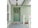 View of a green front door with decorative wreath, hanging light fixture and adjacent window at 5825 Meadowpark Pl, Lithia, FL 33547