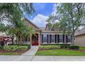 Charming home featuring a red door, dormer windows, and professionally landscaped yard at 10309 Marchmont Ct, Tampa, FL 33626