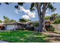 Charming single-story home boasts a lush lawn, mature trees, and a two-car garage at 1041 Persimmon Dr, Palm Harbor, FL 34683