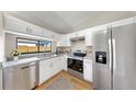 Modern kitchen with stainless steel appliances, granite countertops, white cabinets, and a view to the backyard at 11301 Hedgemore Dr, Tampa, FL 33624