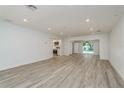 Open-concept living room with light wood-look floors and recessed lighting, connecting to the kitchen and outdoor pool area at 1152 Jackmar Rd, Dunedin, FL 34698