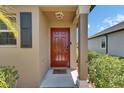A welcoming covered entryway with a bright red front door and lovely landscaped shrubbery at 11707 Sunburst Marble Rd, Riverview, FL 33579