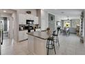 Open-concept kitchen with white cabinets, a center island with bar seating, and stainless steel appliances at 11707 Sunburst Marble Rd, Riverview, FL 33579