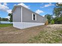 Exterior side view of a gray mobile home with a wooden porch on a large grassy lot at 16137 Melbourne St, Brooksville, FL 34604