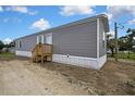 Gray sided mobile home with white trim featuring a wooden porch under a partly cloudy blue sky at 16137 Melbourne St, Brooksville, FL 34604