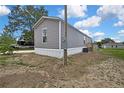 Exterior side view of a gray mobile home with siding and white trim with a large yard at 16137 Melbourne St, Brooksville, FL 34604