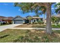 Charming single-story home with a well-maintained lawn, palm trees, and two-car garage at 16516 Bridgewalk Dr, Lithia, FL 33547