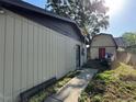 A backyard view shows siding on a home with a detached garage with a red door at 1703 N Taylor Rd, Brandon, FL 33510