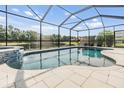 Screened-in pool with a waterfall feature and view of the pond at 19837 Lonesome Pine Dr, Land O Lakes, FL 34638
