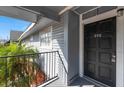 Charming condo balcony with gray wood siding, black door and black iron railing at 200 Country Club Dr # 906, Largo, FL 33771