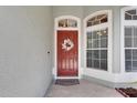 Close-up of welcoming red front door, decorative wreath, and sidelight windows at 2010 Rutherford Dr, Dover, FL 33527