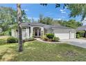 Charming single-story home featuring lush landscaping, a red door, and a three-car garage at 2010 Rutherford Dr, Dover, FL 33527