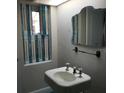 Cozy bathroom with a stylish pedestal sink, unique shuttered window, and decorative mirror at 2101 Sunset Point Rd # 2305, Clearwater, FL 33765