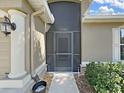 View of front door behind screen, with a pillar, and landscaping at 2405 Dakota Rock Dr, Ruskin, FL 33570