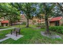 Exterior of building with a green lawn, shade trees, and a park bench at 3062 Eastland Blvd # 402, Clearwater, FL 33761