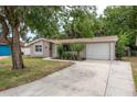 Inviting single-story home featuring a well-manicured lawn, attached garage, and lush landscaping at 3601 Grayton Dr, New Port Richey, FL 34652