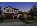 Charming two-story home at dusk with warm lighting and a well-maintained yard at 5043 Night Star Trl, Odessa, FL 33556
