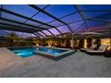 A screened in pool and integrated spa are illuminated at dusk, with lounge chairs nearby at 5043 Night Star Trl, Odessa, FL 33556