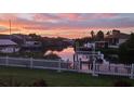 Waterfront view of grassy yard with a white fence, boat dock, and stunning sunset reflections at 6604 Dolphin Cove Dr, Apollo Beach, FL 33572