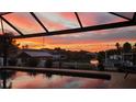 Relaxing screened-in pool area with picturesque sunset views over the tranquil waterfront canal at 6604 Dolphin Cove Dr, Apollo Beach, FL 33572
