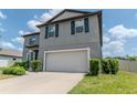 Gray two-story home featuring a two-car garage, manicured landscaping, and complementary dark shutters at 6653 Mineral Springs Rd, New Port Richey, FL 34653