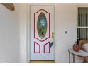 Close-up of a decorative front door with an oval window and pink trim, offering a warm welcome at 9013 Nakoma Way, Weeki Wachee, FL 34613