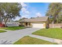 Inviting home with a green lawn, mature trees, and a driveway leading to an attached two-car garage at 1017 Hamilton Ave, Tarpon Springs, FL 34689