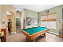 Spacious game room featuring a pool table, large window, and neutral-toned walls at 11845 Newberry Grove Loop, Riverview, FL 33579
