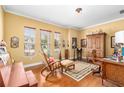 Well-lit home office with wooden furniture, hardwood floors, and three windows at 11845 Newberry Grove Loop, Riverview, FL 33579